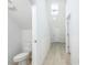 Well-lit hallway with vinyl flooring and a view of a toilet in a half-bathroom at 164 14Th Ave, Longwood, FL 32750