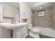 Stylish bathroom features pedestal sink, unique stone-look tile surround, and stone floors at 175 Cliff St, Deland, FL 32720