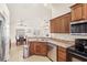 Open kitchen featuring stainless steel appliances, wooden cabinetry, and views into the dining area at 1880 Lorraine Way, St Cloud, FL 34769