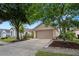 Single-story home with large mature shade tree, two-car garage and sidewalk at 1919 River Park Blvd, Orlando, FL 32817