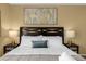 Comfortable bedroom featuring a queen bed, nightstands, lamps, and decorative artwork at 217 Holborn Loop, Davenport, FL 33897