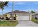 Charming yellow home featuring a two-car garage, well-maintained lawn, and inviting curb appeal at 217 Holborn Loop, Davenport, FL 33897