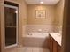 Bright bathroom with a soaking tub, tiled walls, vanity with double sinks, and glass enclosed walk-in shower at 225 Vista Dr, Davenport, FL 33897