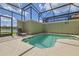 Screened-in pool area with lounge chair and lake view beyond at 3055 Beach Palm Ave, Kissimmee, FL 34747