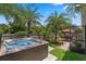 Backyard featuring a hot tub, patio area, hammock, mature trees, and lush landscaping at 3188 Verbena Ct, Deltona, FL 32725