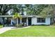 Charming single-story home boasts a lush green lawn, complemented by mature trees and manicured landscaping at 3474 Fairway Ln, Orlando, FL 32804
