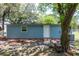 Back view of the home featuring blue siding, white door, and a compact layout, surrounded by mature trees at 4515 Isaac Ln, Sanford, FL 32771