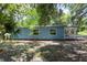 Home featuring blue siding with bright windows, and front porch with white railings under a shady tree canopy at 4515 Isaac Ln, Sanford, FL 32771