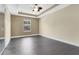 Spacious bedroom featuring a ceiling fan, tray ceiling, and gray wood-look floors at 617 Joyful Blossom Pl, Longwood, FL 32750