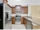 Kitchen boasts stainless steel appliances, brown cabinets, granite countertops, and tile floors at 617 Joyful Blossom Pl, Longwood, FL 32750