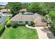 Aerial view of a well-maintained single-story home with lush landscaping, pool, and brick paver driveway at 7549 Lake Marsha Dr, Orlando, FL 32819