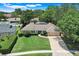 Aerial view of a well-maintained single-story home with lush landscaping, pool, and brick paver driveway at 7549 Lake Marsha Dr, Orlando, FL 32819