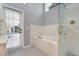 Bathroom with a door to the patio, a modern tub, updated tilework, and frameless glass shower at 7549 Lake Marsha Dr, Orlando, FL 32819