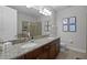 Bathroom featuring double sinks, granite countertops, a large mirror, and a tiled shower enclosure at 7739 Graben St, Kissimmee, FL 34747