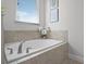A luxurious soaking tub with tile surround and bright natural light from a nearby window at 7739 Graben St, Kissimmee, FL 34747