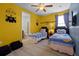 bedroom featuring two twin beds, bright yellow walls with Minion accents, and an attached bathroom at 7739 Graben St, Kissimmee, FL 34747
