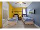 bedroom featuring two twin beds, bright yellow walls with Minion accents, and an attached bathroom at 7739 Graben St, Kissimmee, FL 34747