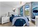 Cozy bedroom features modern decor, accent wall with feather wallpaper, and a bright, sun-filled window at 8187 Roseville Rd, Davenport, FL 33896