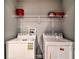 Functional laundry room with white washer and dryer, plus convenient upper shelving for storage at 8187 Roseville Rd, Davenport, FL 33896