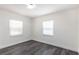 This is a simple bedroom with grey wood-look flooring and two windows at 88 E Charlotte Ave, Eustis, FL 32726