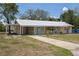 Charming single-story home featuring a metal roof, pale yellow exterior and a long driveway at 88 E Charlotte Ave, Eustis, FL 32726