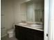 Bathroom with double sinks, dark cabinets, and well-lit mirror at 8933 Hinsdale Heights Dr, Polk City, FL 33868