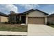 Beige single-story home featuring an attached two-car garage, manicured lawn, and carefully placed landscaping at 8933 Hinsdale Heights Dr, Polk City, FL 33868