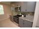 A close up of the modern kitchen with stainless steel appliances, granite counters and gray cabinets at 971 Desert Candle Dr, Ocoee, FL 34761