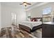 Bright bedroom featuring tray ceilings, wood floors, two windows, and a glimpse into the attached bathroom at 10111 Tierra Bella Dr, Orlando, FL 32825