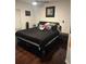 Comfortable bedroom with black bedding, modern furniture, and dark hardwood floors at 10148 Malpas Pt, Orlando, FL 32832
