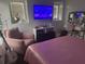 A cozy bedroom featuring a pink bed and chair, entertainment center with tv, and vanity area at 10148 Malpas Pt, Orlando, FL 32832