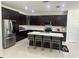 Spacious kitchen with dark wood cabinetry, a stainless steel refrigerator, and a large island with counter seating at 10148 Malpas Pt, Orlando, FL 32832
