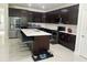 Modern kitchen with dark wood cabinets, stainless steel appliances, and a large center island with bar seating at 10148 Malpas Pt, Orlando, FL 32832