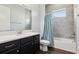 Well-lit bathroom featuring a shower-tub combo with tile surround and dark vanity at 10203 Henbury St, Orlando, FL 32832