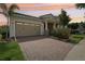 Charming single-story home with a brick driveway, lush landscaping, and a welcoming covered entrance at sunset at 10203 Henbury St, Orlando, FL 32832