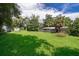 Large backyard with green grass, mature trees, and a storage shed at 1121 Votaw Rd, Apopka, FL 32703