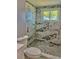 This contemporary bathroom features marble tiling, pebble flooring, and a window above the toilet at 11373 Darlington Dr, Orlando, FL 32837