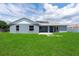 Backyard featuring a well-maintained lawn, an open patio, and solar panels on the roof at 1195 Tivoli Dr, Deltona, FL 32725