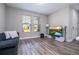 Bright living room with wood floors, a modern TV setup, and a comfortable dark gray sofa at 12133 Bracco St, Winter Garden, FL 34787