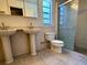Bright bathroom featuring dual pedestal sinks, a toilet, and a glass-enclosed shower stall, ideal for efficient use at 1219 Serissa Ct, Orlando, FL 32818