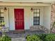 A bright red front door with sidelights and sconce lighting creates a charming entryway to the home at 1219 Serissa Ct, Orlando, FL 32818