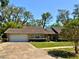 Charming single-story home featuring a well-manicured lawn, stone accents, and an attached two car garage at 1219 Serissa Ct, Orlando, FL 32818