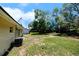 Spacious backyard with grass and trees, and the home's exterior and AC unit visible at 14 Cyclops Dr, Apopka, FL 32703