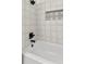 Bright bathroom features white tile, dark fixtures, and decorative backsplash in niche at 1401 Canberra Ave, Orlando, FL 32806
