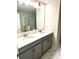 Modern bathroom featuring double vanity, gray cabinets and large mirror with lighting at 1513 Maidstone Ct, Davenport, FL 33896