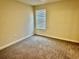 A bright bedroom offers neutral walls and carpet and a single, sun-filled window at 1513 Maidstone Ct, Davenport, FL 33896