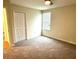 A simple bedroom offers neutral walls and carpet and a single, sun-filled window at 1513 Maidstone Ct, Davenport, FL 33896