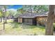 Home's backyard showcasing a covered patio, lush green grass, and mature trees for outdoor living at 1803 Foxhall Cir # 1803, Kissimmee, FL 34741