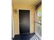 Screened patio entry showing a solid black door with tan siding and black tiled floors at 1950 Summer Club Dr # 202, Oviedo, FL 32765