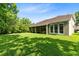 Large backyard with lush green grass, mature trees, and a view of the house with a screened patio at 2607 Stanmore Ct, Orlando, FL 32817